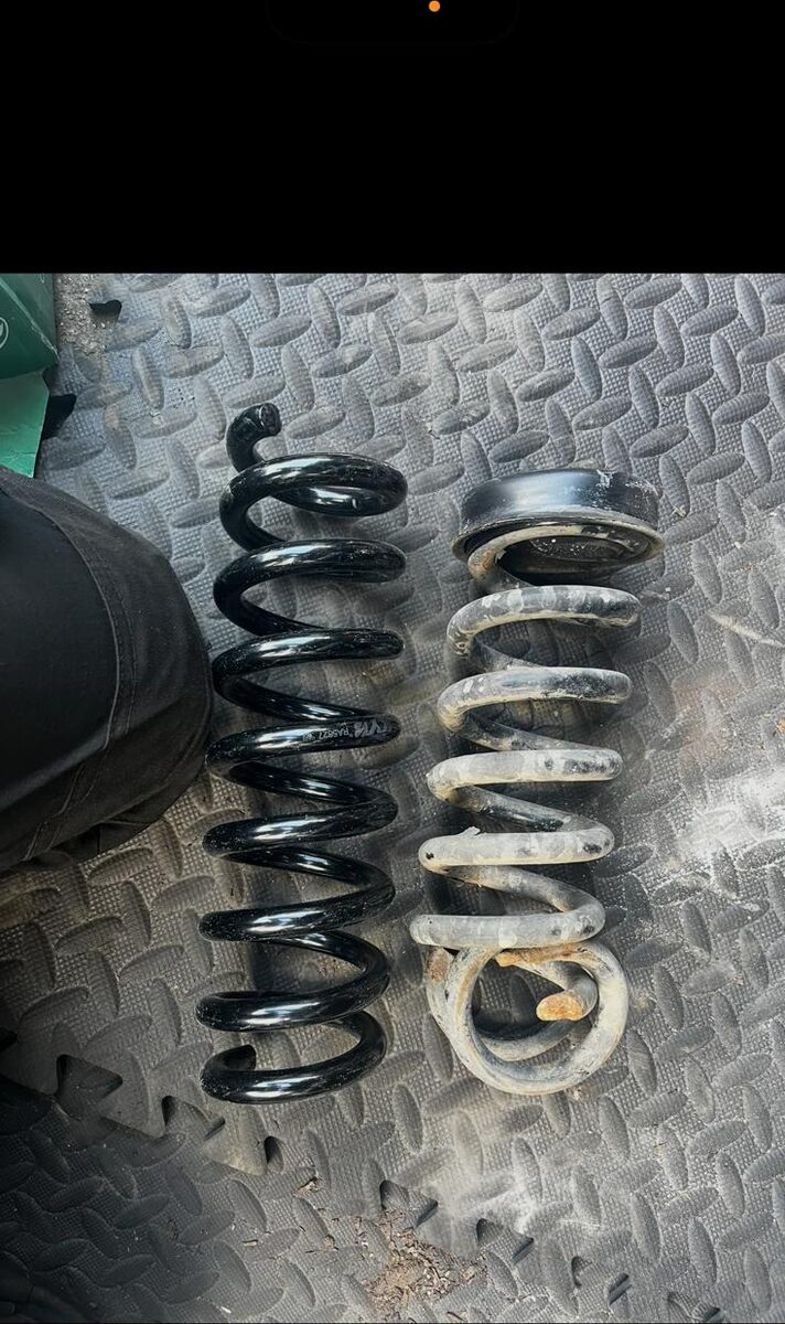 New coil spring next to a corroded old coil spring