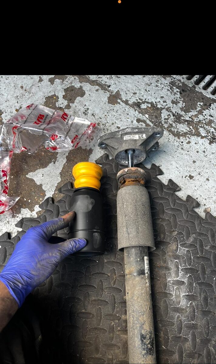 New shock absorber next to the worn unit removed from the car