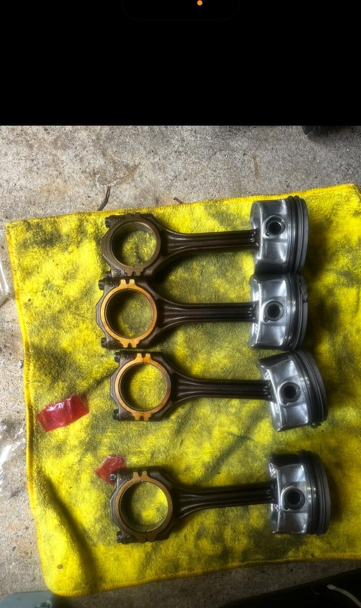 Set of pistons and connecting rods laid out on a workshop cloth